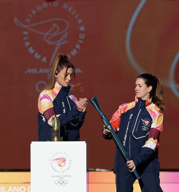(251207) -- ROME, Dec. 7, 2025 (Xinhua) -- A staff member lights a torch with the fire from the lantern during the torch relay for 2026 Milan-Cortina Winter Olympics at the Stadio dei Marmi in Rome, Italy, Dec. 6, 2025. (Xinhua/Li Jing)