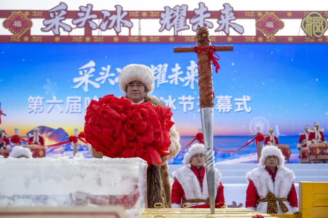 (251207) -- HARBIN, Dec. 7, 2025 (Xinhua) -- A crew member displays the first ice cube collected during an ice collecting festival in Harbin, northeast China's Heilongjiang Province, Dec. 7, 2025. Marking the beginning of Harbin's ice collecting season, the sixth ice collecting festival kicked off here by the Songhua River on Sunday, attracting lots of people with ice collecting ceremony and folk custom experience activities. (Xinhua/Zhang Tao)
