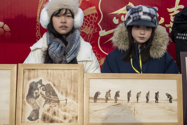 (251207) -- HARBIN, Dec. 7, 2025 (Xinhua) -- Students display their artworks during an ice collecting festival in Harbin, northeast China's Heilongjiang Province, Dec. 7, 2025. Marking the beginning of Harbin's ice collecting season, the sixth ice collecting festival kicked off here by the Songhua River on Sunday, attracting lots of people with ice collecting ceremony and folk custom experience activities. (Xinhua/Zhang Tao)