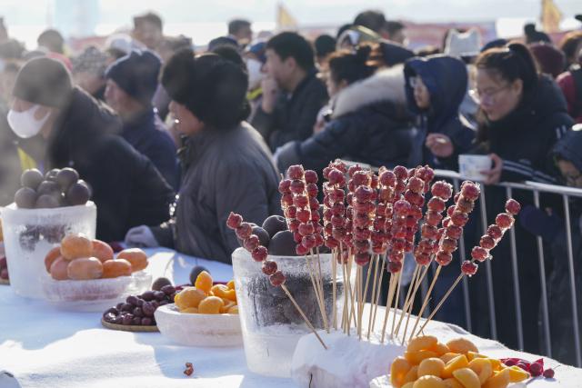 (251207) -- HARBIN, Dec. 7, 2025 (Xinhua) -- Fruits and local snacks are pictured at a market during an ice collecting festival in Harbin, northeast China's Heilongjiang Province, Dec. 7, 2025. Marking the beginning of Harbin's ice collecting season, the sixth ice collecting festival kicked off here by the Songhua River on Sunday, attracting lots of people with ice collecting ceremony and folk custom experience activities. (Xinhua/Wang Song)