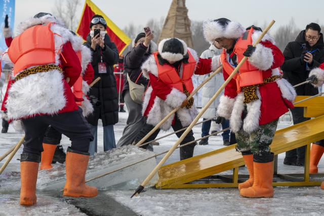 (251207) -- HARBIN, Dec. 7, 2025 (Xinhua) -- Crew members collect the first ice cube during an ice collecting festival in Harbin, northeast China's Heilongjiang Province, Dec. 7, 2025. Marking the beginning of Harbin's ice collecting season, the sixth ice collecting festival kicked off here by the Songhua River on Sunday, attracting lots of people with ice collecting ceremony and folk custom experience activities. (Xinhua/Zhang Tao)