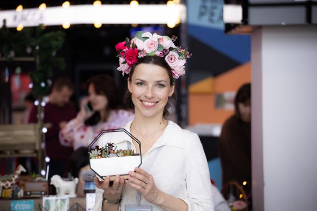 (251207) -- VLADIVOSTOK, Dec. 7, 2025 (Xinhua) -- A woman poses for a photo with a potted plant at a plant and flower market in Vladivostok, Russia, Dec. 7, 2025. (Photo by Andrey Matveenko/Xinhua)