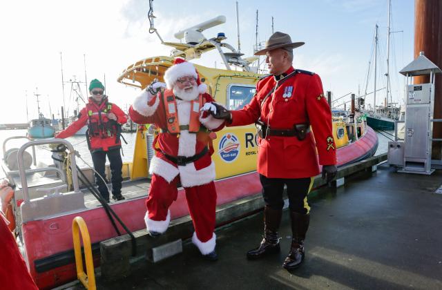 (251208) -- BEIJING, Dec. 8, 2025 (Xinhua) -- A member of the Royal Canadian Mounted Police assists a man dressed as Santa Claus as the latter disembarks from a boat at Fisherman's Wharf in Steveston Village, Richmond, British Columbia, Canada, Dec. 7, 2025.
  The Santa Claus's arrival event was held here on Sunday, marking the opening of local Christmas celebrations and drawing hundreds of residents to attend. (Photo by Liang Sen/Xinhua)