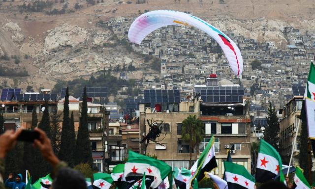 (251208) -- DAMASCUS, Dec. 8, 2025 (Xinhua) -- A military paraglider performs during a military parade marking the first anniversary of Syria's political transition in Damascus, Syria, Dec. 8, 2025. Syria's interim authorities staged a major military parade in the capital, Damascus, on Monday to mark the first anniversary of the country's political transition. (Photo by Ammar Safarjalani/Xinhua)