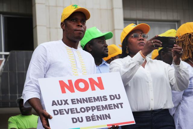 (251209) -- COTONOU, Dec. 9, 2025 (Xinhua) -- A man holds a sign showing support for Beninese President Patrice Talon at Place Bulgarie in Cotonou, the economic capital of Benin, Dec. 8, 2025.
  Benin's government said on Sunday that an attempted military mutiny had been foiled in Cotonou, the country's economic capital and largest city, after armed soldiers briefly took over state television to declare President Patrice Talon was removed from office.
  The Presidency said the president is safe and that government forces have regained control of the situation. (Photo by Seraphin Zounyekpe/Xinhua)