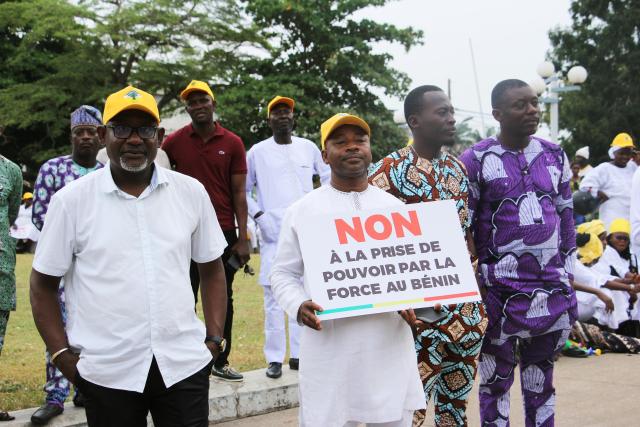 (251209) -- COTONOU, Dec. 9, 2025 (Xinhua) -- A man holds a sign showing support for Beninese President Patrice Talon at Place Bulgarie in Cotonou, the economic capital of Benin, Dec. 8, 2025.
  Benin's government said on Sunday that an attempted military mutiny had been foiled in Cotonou, the country's economic capital and largest city, after armed soldiers briefly took over state television to declare President Patrice Talon was removed from office.
  The Presidency said the president is safe and that government forces have regained control of the situation. (Photo by Seraphin Zounyekpe/Xinhua)