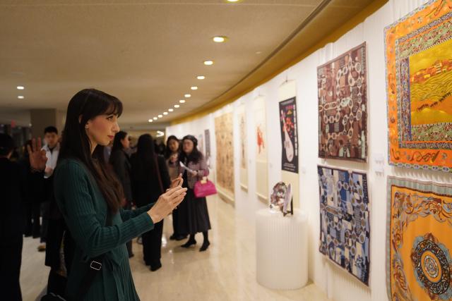 (251209) -- UNITED NATIONS, Dec. 9, 2025 (Xinhua) -- People visit an exhibition showcasing Tsinghua University's research and design work inspired by the ancient art of Dunhuang at the UN headquarters in New York, Dec. 8, 2025. More than 80 works are on display at the exhibition, from early masters such as Pang Xunqin, Chang Sha'na, Chen Hanmin and Liu Jude, to new pieces by Tsinghua students and alumni. (Xinhua/Zhang Fengguo)