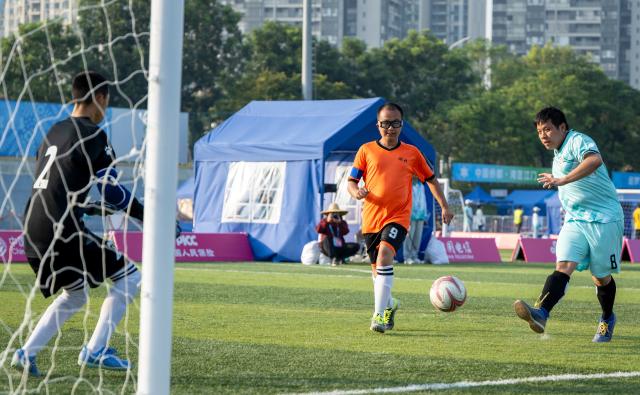 (251209) -- JIANGMEN, Dec. 9, 2025 (Xinhua) -- Lee Ho Ting (R) of Hong Kong shoots during a special olympics football match between Hong Kong and Hubei at China's 12th National Games for Persons with Disabilities and the 9th National Special Olympic Games in Jiangmen, south China's Guangdong Province, Dec. 9, 2025. (Xinhua/Sui Shangjun)