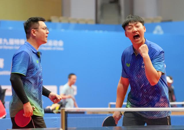 (251209) -- HONG KONG, Dec. 9, 2025 (Xinhua) -- Wu Bairong (R)/Zhang Liangzhong of Jiangsu react during the men's doubles age 30+ group A match of special olympics table tennis at China's 12th National Games for Persons with Disabilities and the 9th National Special Olympic Games in Hong Kong, south China, Dec. 9, 2025. (Xinhua/Zhu Zheng)