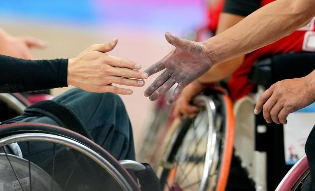 (251210) -- BEIJING, Dec. 10, 2025 (Xinhua) -- Tenzin (R) of Xizang shakes hands with a player of Liaoning after the men's wheelchair basketball match between Liaoning and Xizang at China's 12th National Games for Persons with Disabilities and the 9th National Special Olympic Games in Guangzhou, south China's Guangdong Province, Dec. 9, 2025. (Xinhua/Wu Lu)