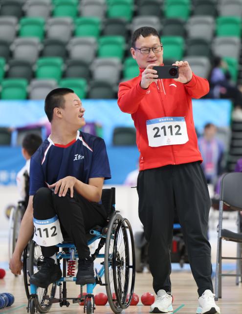(251210) -- HONG KONG, Dec. 10, 2025 (Xinhua) -- Wang Shibo (L) of Heilongjiang takes photos with his coach after the men's individual BC1 round robin match of boccia at China's 12th National Games for Persons with Disabilities and the 9th National Special Olympic Games in Hong Kong, south China, Dec. 10, 2025. (Xinhua/Lu Hanxin)