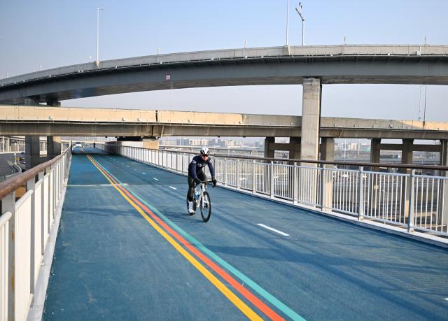 (251210) -- SHIJIAZHUANG, Dec. 10, 2025 (Xinhua) -- A cyclist rides on a bridge which is part of an urban ring greenway across the Shijiazhuang-Taiyuan railway in Shijiazhuang, north China's Hebei Province, on Dec. 10, 2025. The 101-kilometer-long urban ring greenway in Shijiazhuang was made fully accessible to the public on Wednesday. The road facility links multiple waterways as well as 76 parks in the city, providing rich recreational experiences. (Xinhua/Mu Yu)