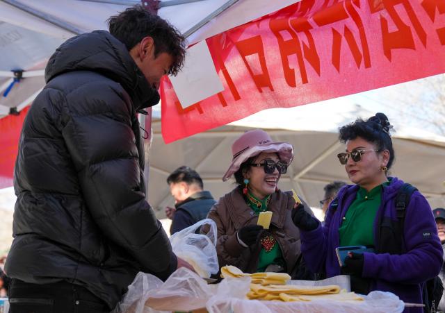 (251210) -- LHASA, Dec. 10, 2025 (Xinhua) -- People select products during a supply and marketing fair at a park in Lhasa, southwest China's Xizang Autonomous Region, Dec. 10, 2025. The event has gathered more than 1,000 characteristic agricultural products from Xizang, including highland barley products, yak meat products, dairy products and so on, providing a platform for farmers and herdsmen to increase their income and people to purchase authentic specialties. (Xinhua/Jigme Dorje)