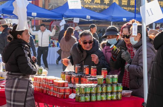 (251210) -- LHASA, Dec. 10, 2025 (Xinhua) -- People select products during a supply and marketing fair at a park in Lhasa, southwest China's Xizang Autonomous Region, Dec. 10, 2025. The event has gathered more than 1,000 characteristic agricultural products from Xizang, including highland barley products, yak meat products, dairy products and so on, providing a platform for farmers and herdsmen to increase their income and people to purchase authentic specialties. (Xinhua/Jigme Dorje)