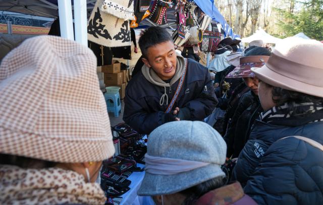 (251210) -- LHASA, Dec. 10, 2025 (Xinhua) -- A merchant introduces products to customers during a supply and marketing fair at a park in Lhasa, southwest China's Xizang Autonomous Region, Dec. 10, 2025. The event has gathered more than 1,000 characteristic agricultural products from Xizang, including highland barley products, yak meat products, dairy products and so on, providing a platform for farmers and herdsmen to increase their income and people to purchase authentic specialties. (Xinhua/Jigme Dorje)