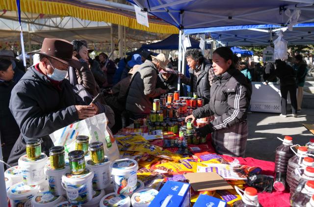 (251210) -- LHASA, Dec. 10, 2025 (Xinhua) -- People select products during a supply and marketing fair at a park in Lhasa, southwest China's Xizang Autonomous Region, Dec. 10, 2025. The event has gathered more than 1,000 characteristic agricultural products from Xizang, including highland barley products, yak meat products, dairy products and so on, providing a platform for farmers and herdsmen to increase their income and people to purchase authentic specialties. (Xinhua/Jigme Dorje)