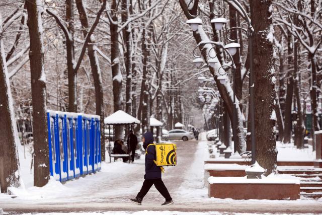 (251210) -- BISHKEK, Dec. 10, 2025 (Xinhua) -- A deliveryman walks in a street after snow in Bishkek, Kyrgyzstan, Dec. 10, 2025. (Photo by Roman/Xinhua)