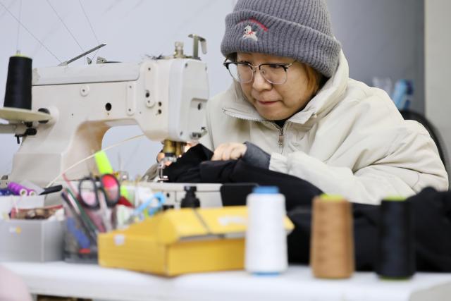 (251210) -- TIANJIN, Dec. 10, 2025 (Xinhua) -- A shopkeeper mends clothes at a shop in the "repair alley" in north China's Tianjin, Dec. 9, 2025. A "repair alley" established in June 2024 has become a lively hub for neighborhood-friendly repair services in Tianjin. In this dedicated zone, local residents have easy access to daily services such as knife sharpening, darning, locksmiths and watch repair. (Xinhua/Li Ran)