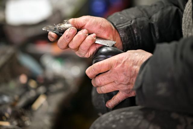 (251210) -- TIANJIN, Dec. 10, 2025 (Xinhua) -- A cobbler repairs a shoe at a shop in the "repair alley" in north China's Tianjin, Dec. 9, 2025. A "repair alley" established in June 2024 has become a lively hub for neighborhood-friendly repair services in Tianjin. In this dedicated zone, local residents have easy access to daily services such as knife sharpening, darning, locksmiths and watch repair. (Xinhua/Zhang Cheng)
