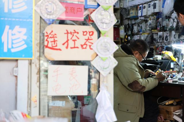 (251210) -- TIANJIN, Dec. 10, 2025 (Xinhua) -- A technician repairs a home appliance at a shop in the "repair alley" in north China's Tianjin, Dec. 9, 2025. A "repair alley" established in June 2024 has become a lively hub for neighborhood-friendly repair services in Tianjin. In this dedicated zone, local residents have easy access to daily services such as knife sharpening, darning, locksmiths and watch repair. (Xinhua/Li Ran)