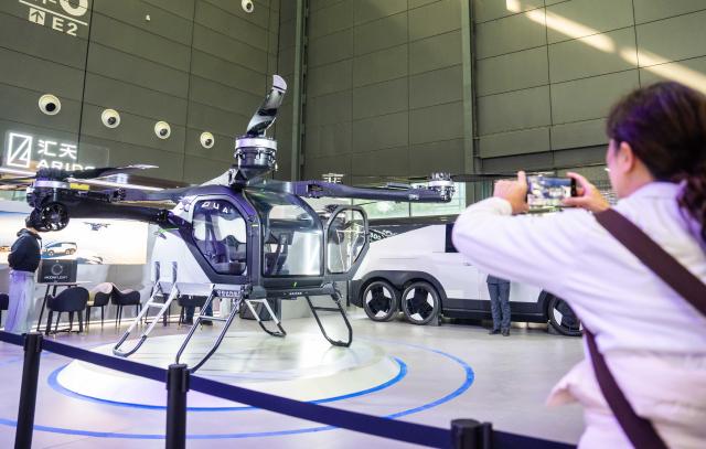 (251211) -- BEIJING, Dec. 11, 2025 (Xinhua) -- A visitor takes photos of the flight module of a flying car on display at the 21st Changsha  International Automobile Expo in Changsha, central China's Hunan Province, on Dec. 10, 2025. The 6-day expo kicked off on Wednesday at the Changsha International Convention and Exhibition Center, showcasing some 1,000 vehicles from over 70 automobile brands. (Xinhua/Chen Sihan)