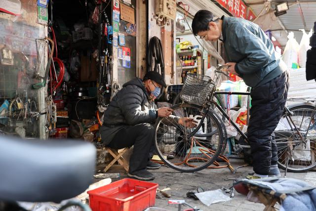 (251211) -- BEIJING, Dec. 11, 2025 (Xinhua) -- A shopkeeper (L) repairs a bicycle at a shop in the "repair alley" in north China's Tianjin, Dec. 9, 2025. A "repair alley" established in June 2024 has become a lively hub for neighborhood-friendly repair services in Tianjin. In this dedicated zone, local residents have easy access to daily services such as knife sharpening, darning, locksmiths and watch repair. (Xinhua/Li Ran)