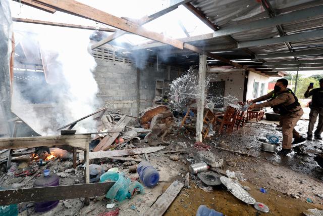 (251211) -- SURIN PROVINCE, Dec. 11, 2025 (Xinhua) -- A Thai police officer splashes water to control fire at a house damaged by artillery in Surin province, Thailand, Dec. 11, 2025. Thai Defense Ministry spokesperson Surasant Kongsiri said on Thursday that the ongoing border clashes with Cambodia have left nine Thai soldiers dead and more than 120 people injured. (Xinhua)