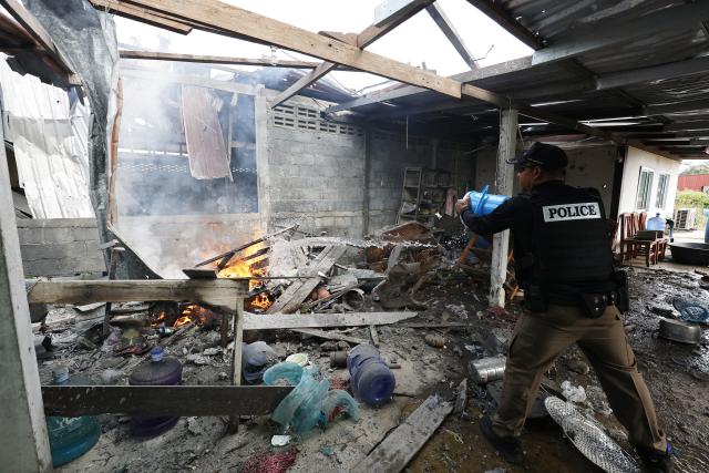 (251211) -- SURIN PROVINCE, Dec. 11, 2025 (Xinhua) -- A Thai police officer splashes water to control fire at a house damaged by artillery in Surin province, Thailand, Dec. 11, 2025. Thai Defense Ministry spokesperson Surasant Kongsiri said on Thursday that the ongoing border clashes with Cambodia have left nine Thai soldiers dead and more than 120 people injured. (Xinhua)