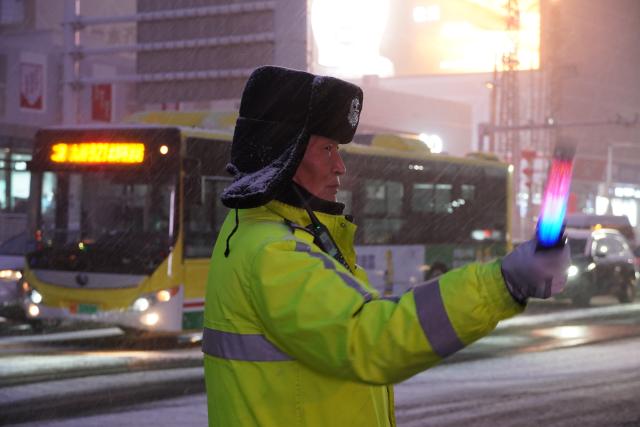 (251211) -- URUMQI, Dec. 11, 2025 (Xinhua) -- A police officer directs traffic in Urumqi, northwest China's Xinjiang Uygur Autonomous Region, Dec. 11, 2025. TO GO WITH "Xinjiang heats up, halts traffic amid strong cold snap" (Photo by Akbar Ablat/Xinhua)