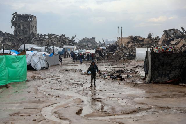 (251211) -- GAZA, Dec. 11, 2025 (Xinhua) -- A displaced Palestinian child stands outside during a rain in the Zeitoun neighborhood, southeast of Gaza City, on Dec. 11, 2025. Heavy winter rains and high winds are pounding flimsy temporary shelters of tents and tarps in the Gaza Strip, putting more vulnerable people at risk, UN humanitarians said on Wednesday. (Photo by Rizek Abdeljawad/Xinhua)