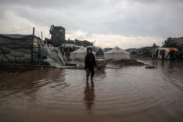 (251211) -- GAZA, Dec. 11, 2025 (Xinhua) -- A displaced Palestinian child stands outside during a rain in the Zeitoun neighborhood, southeast of Gaza City, on Dec. 11, 2025. Heavy winter rains and high winds are pounding flimsy temporary shelters of tents and tarps in the Gaza Strip, putting more vulnerable people at risk, UN humanitarians said on Wednesday. (Photo by Rizek Abdeljawad/Xinhua)