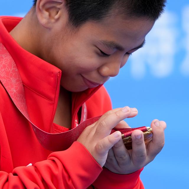 (251212) -- BEIJING, Dec. 12, 2025 (Xinhua) -- Gold medalist Wan Jiahao of Jiangxi touches his medal during the awarding ceremony for the men's age 8-11 group 200m of special olympics athletics at China's 12th National Games for Persons with Disabilities and the 9th National Special Olympic Games in Zhongshan, south China's Guangdong Province, Dec. 11, 2025. (Xinhua/Yang Chenguang)