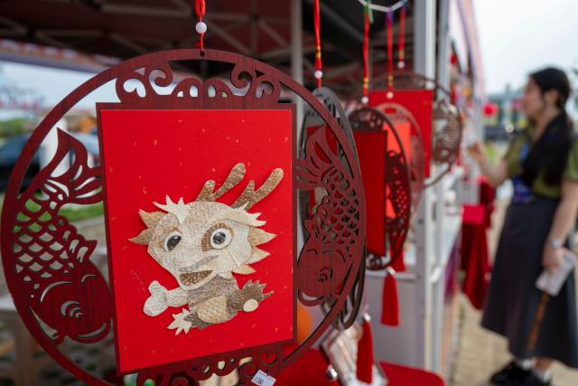 (251212) --  HARBIN, Dec. 12, 2025 (Xinhua) -- Visitors look at fish skin handicrafts of the Hezhe ethnic group in Fuyuan, northeast China's Heilongjiang Province, July 1, 2025. TO GO WITH "China Focus: From survival to revival, ancient Hezhen ethnic art breathes new life" (Xinhua/Zhang Tao)