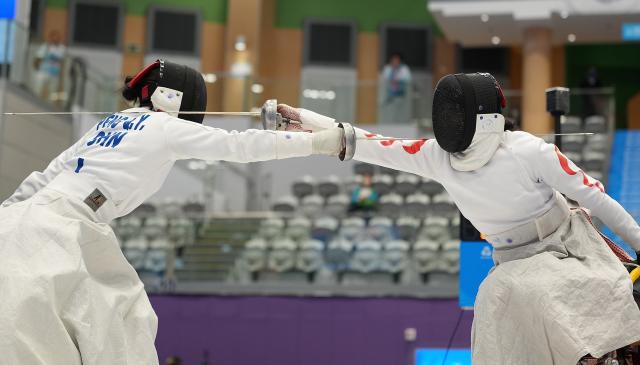 (251212) -- HONG KONG, Dec. 12, 2025 (Xinhua) -- Peng Qiyuan (L) of Shanghai-Guangdong United Team competes against Zou Xufeng of Team Shanghai during the women's epee team final of wheelchair fencing at China's 12th National Games for Persons with Disabilities and the 9th National Special Olympic Games in Hong Kong, south China, Dec. 12, 2025. (Xinhua/Hou Zhaokang)