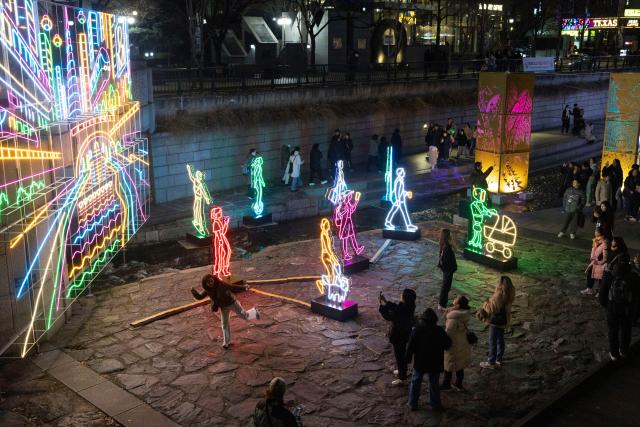 (251212) -- SEOUL, Dec. 12, 2025 (Xinhua) -- People view light installations of the 2025 Seoul Winter Festa at the Cheonggye stream in Seoul, South Korea, Dec. 12, 2025. (Photo by Jun Hyosang/Xinhua)