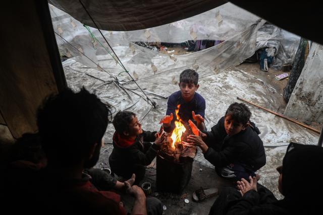 (251212) -- GAZA, Dec. 12, 2025 (Xinhua) -- Palestinians sit around a brazier to stay warm after rain at a temporary shelter in Gaza City, on Dec. 12, 2025. At least 14 people were killed in the Gaza Strip over the past 24 hours as homes collapsed and tents sheltering displaced families were flooded during a powerful winter storm, Gaza's Civil Defense said on Friday. (Photo by Rizek Abdeljawad/Xinhua)