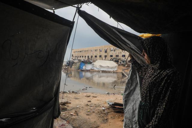 (251212) -- GAZA, Dec. 12, 2025 (Xinhua) -- A Palestinian woman looks out from her temporary shelter after rain in Gaza City, on Dec. 12, 2025. At least 14 people were killed in the Gaza Strip over the past 24 hours as homes collapsed and tents sheltering displaced families were flooded during a powerful winter storm, Gaza's Civil Defense said on Friday. (Photo by Rizek Abdeljawad/Xinhua)