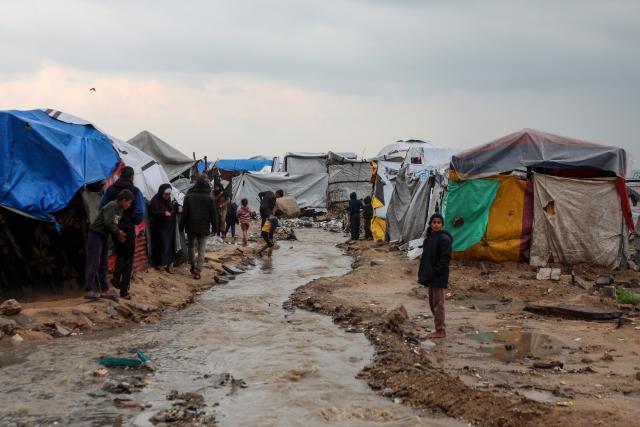 (251212) -- GAZA, Dec. 12, 2025 (Xinhua) -- Palestinians come outside their temporary shelters after rain in Gaza City, on Dec. 12, 2025. At least 14 people were killed in the Gaza Strip over the past 24 hours as homes collapsed and tents sheltering displaced families were flooded during a powerful winter storm, Gaza's Civil Defense said on Friday. (Photo by Rizek Abdeljawad/Xinhua)
