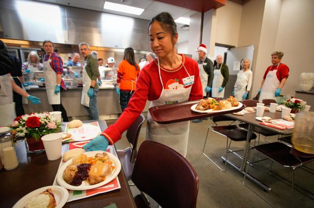 (251213) -- VANCOUVER, Dec. 13, 2025 (Xinhua) -- A volunteer serves food during the annual Christmas meal event in Vancouver, British Columbia, Canada, on Dec. 12, 2025. (Photo by Liang Sen/Xinhua)