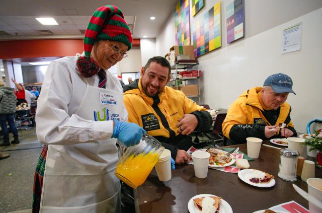 (251213) -- VANCOUVER, Dec. 13, 2025 (Xinhua) -- A volunteer serves drinks during the annual Christmas meal event in Vancouver, British Columbia, Canada, on Dec. 12, 2025. (Photo by Liang Sen/Xinhua)