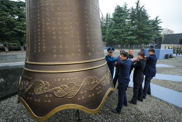 (251213) -- NANJING, Dec. 13, 2025 (Xinhua) -- People strike the Bell of Peace during a national memorial ceremony for the Nanjing Massacre victims held at the Memorial Hall of the Victims in Nanjing Massacre by Japanese Invaders in Nanjing, capital of east China's Jiangsu Province, Dec. 13, 2025. The 12th national memorial day was observed in Nanjing on Saturday to honor about 300,000 victims killed by Japanese troops during the Nanjing Massacre, in a year that marks the 80th anniversary of the end of World War II (WWII). (Xinhua/Li Bo)