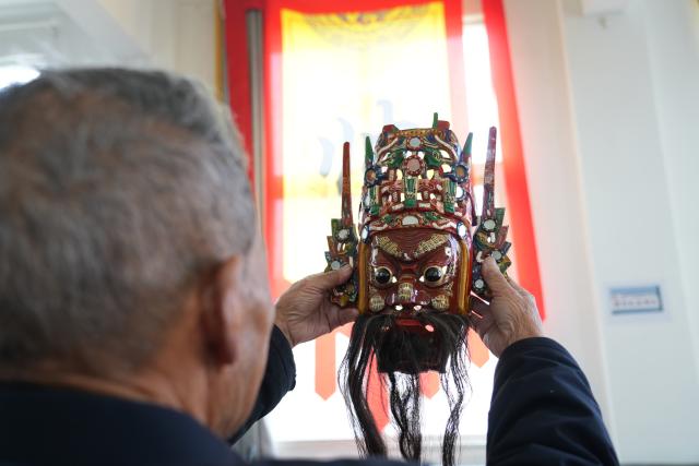 (251213) -- GUIYANG, Dec. 13, 2025 (Xinhua) -- A villager checks a lacquered wooden mask of Dixi opera in Malu Village of Qiannan Buyi and Miao Autonomous Prefecture in southwest China's Guizhou Province, Nov. 20, 2025. TO GO WITH Across China: "Living-fossil" folk opera connects SW China village to its past (Xinhua)