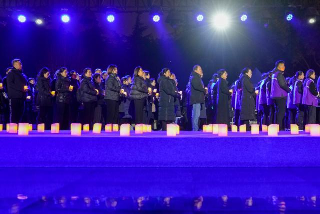 (251213) -- NANJING, Dec. 13, 2025 (Xinhua) -- People attend a candle-light vigil at the Memorial Hall of the Victims in Nanjing Massacre by Japanese Invaders in Nanjing, capital of east China's Jiangsu Province, Dec. 13, 2025. A candle-light vigil was held at the memorial hall on Saturday, which was the 12th national memorial day for the victims of the Nanjing Massacre. (Xinhua/Li Bo)
