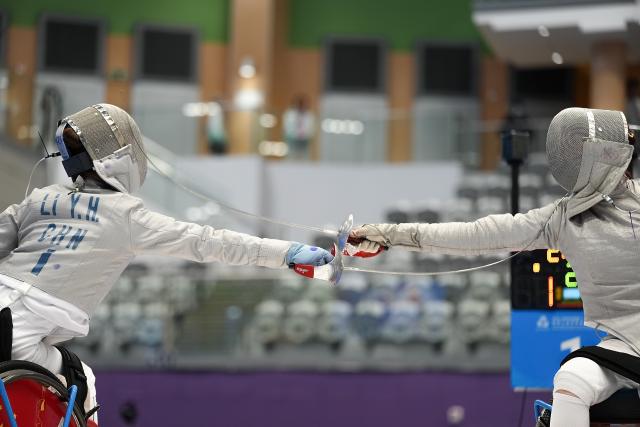 (251213) -- HONG KONG, Dec. 13, 2025 (Xinhua) -- Gu Haiyan (R) of Shanghai and Li Yuehan of Jiangsu compete during the quarterfinals of the women's sabre individual category A wheelchair fencing at China's 12th National Games for Persons with Disabilities and the 9th National Special Olympic Games in Hong Kong, south China, Dec. 13, 2025. (Xinhua/Hou Zhaokang)