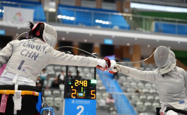 (251213) -- HONG KONG, Dec. 13, 2025 (Xinhua) -- Gu Haiyan (R) of Shanghai and Peng Qiyuan of Shanghai compete during the final of the women's sabre individual category A wheelchair fencing at China's 12th National Games for Persons with Disabilities and the 9th National Special Olympic Games in Hong Kong, south China, Dec. 13, 2025. (Xinhua/Hou Zhaokang)