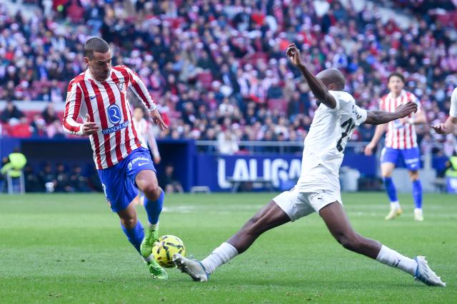 (251214) -- MADRID, Dec. 14, 2025 (Xinhua) -- Atletico de Madrid's Antoine Griezmann (L) vies with Valencia C.F.'s Dimitri Foulquier during the Laliga football match between Atletico de Madrid and Valencia C.F. in Madrid, Spain, Dec. 13, 2025. (Photo by Gustavo Valiente/Xinhua)