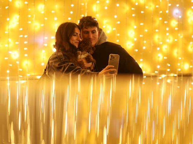 (251214) -- ROME, Dec. 14, 2025 (Xinhua) -- People take selfies with festive lights near Piazza del Popolo in Rome, Italy, Dec. 13, 2025. (Xinhua/Li Jing)