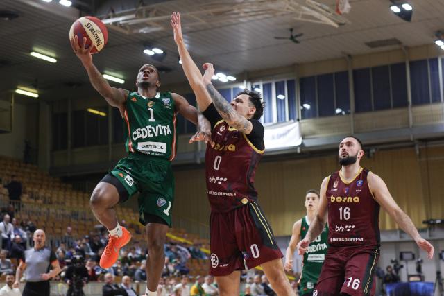 (251214) -- LJUBLJANA, Dec. 14, 2025 (Xinhua) -- Umoja Gibson (L) of Cedevita Olimpija goes for a layup during the 10th round match between Cedevita Olimpija and Bosna BH Telekom at the AdmiralBet ABA Basketball League 2025/26 in Ljubljana, Slovenia, Dec. 13, 2025. (Photo by Zeljko Stevanic/Xinhua)