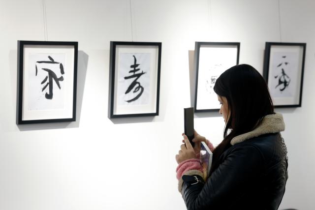 (251214) -- BUCHAREST, Dec. 14, 2025 (Xinhua) -- A visitor takes pictures of Chinese traditional calligraphy during the opening day of the 4th edition of the Buchina Book Fair at the China Cultural Center in Bucharest, Romania, Dec. 13, 2025. Buchina is a book fair dedicated to Chinese literature, culture and art. (Photo by Cristian Cristel/Xinhua)