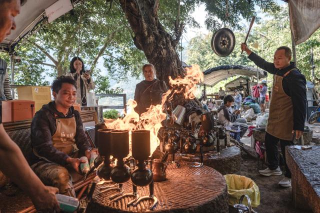 (251214) -- KUNMING, Dec. 14, 2025 (Xinhua) -- Staff members make coffee at a cafe run by Li Jinhe in Mangkuan Township of Baoshan City, southwest China's Yunnan Province, Nov. 15, 2025.
  Mandabatmaz, a Turkish cafe, is located in a small alley beside Istiklal Avenue in Istanbul.
  The owner, Can Ozmen, took over this small coffee shop with a history of nearly sixty years from his parents. To carry on the tradition, he still insists on brewing coffee with copper pots. Ozmen introduced that Turkish coffee should be consumed with coffee grounds, which makes Turkish coffee unique. "Unlike other coffees, which are filtered, Turkish coffee is enjoyed in its entirety," Ozmen explained.
  Turkish coffee has a long history and was inscribed on UNESCO's Representative List of the Intangible Cultural Heritage of Humanity in 2013.
  While in China, a riverside cafe in Yunnan also wins fame among coffee lovers.
  Li Jinhe, 53, has operated his cafe in Mangkuan under Baoshan City in Gaoligong Mountains for 14 years.
  His "flame-brewed coffee", which made by a blowtorch to heat beneath siphon pots, has taken the Internet by storm for its originality, turning his cafe into a viral sensation.
  Tourists said that the coffee shop by the Nujiang River has broken the stereotype of urban coffee, and coffee should be a daily drink integrated into life.
  "I grew up here, and love Gaoligong Mountains," said Li. The Gaoligong Mountains, where fertile soil, ideal temperatures and abundant sunlight situate it within the global coffee-growing belt, boast small-bean coffee. "It is my unwavering commitment to promote local small-bean coffee," added Li.
  Although made by different ways, both Turkish and Chinese coffee tell the story of people's pursuit of life with warmth and aroma. (Xinhua/Wang Guansen)